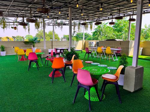 patio z kolorowymi stołami i krzesłami na trawie w obiekcie The कस्तूरी w mieście Maihar