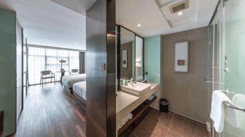 a bathroom with a bed and a sink and a mirror at Hangzhou West Lake Wulin Pagoda Junting Design Hotel in Hangzhou