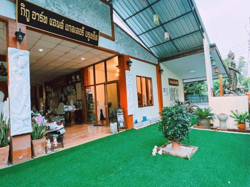 a house with a green carpet in front of it at Phiphu Art and Gallery Boutique Sukhothai in Sukhothai