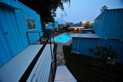 a blue building with a swimming pool next to a house at Sarang by the brook in Kuala Kubu Baharu