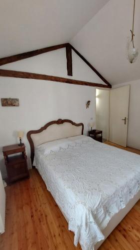 a bedroom with a white bed with a wooden floor at Il Vicoletto in Vittorio Veneto