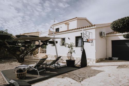 a white house with chairs and a basketball hoop at Oliveres3 in L'Ampolla