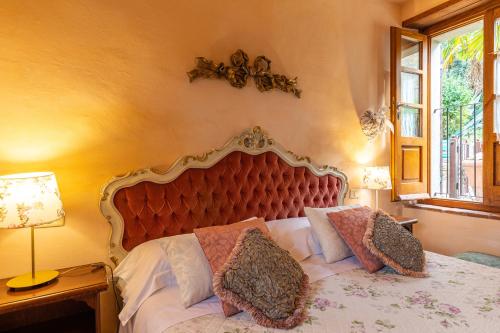 a bedroom with a bed with a large headboard and a window at Borgo Dolci Colline Resort Ziraia in Castiglion Fiorentino