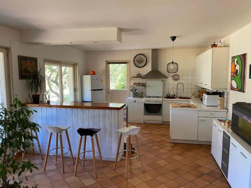 eine Küche mit weißen Schränken und Barhockern in der Unterkunft Calme et tranquillité à la campagne in Charnay