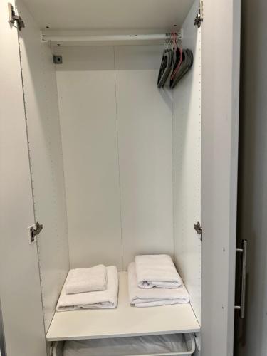 a walk in closet with white cabinets and towels at Luxury Studio Apartment in Harrow on the Hill
