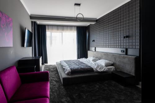 a bedroom with a bed and a couch and a chair at Hotel Javu in Mamaia Nord