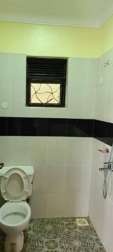 a bathroom with a toilet and a window at Ronnie restate in Jinja