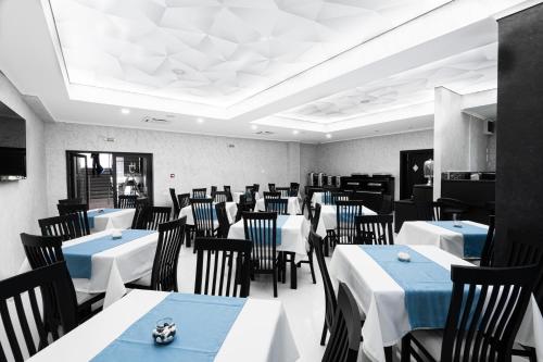 a dining room with white tables and black chairs at Hotel Javu in Mamaia Sat/Năvodari