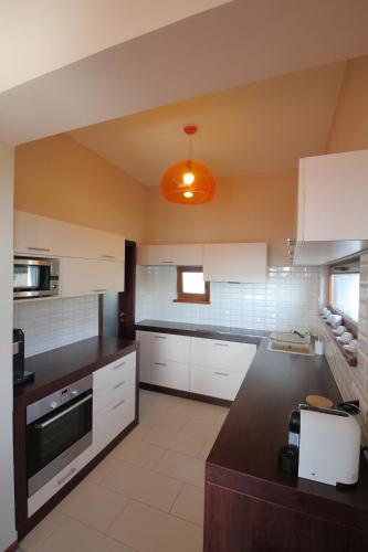uma cozinha com armários brancos e uma luz laranja em August Panorama Apartman em Vác