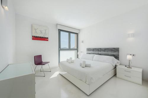 a white bedroom with a bed and a chair at Ático Londres Derecha in Port de Pollensa