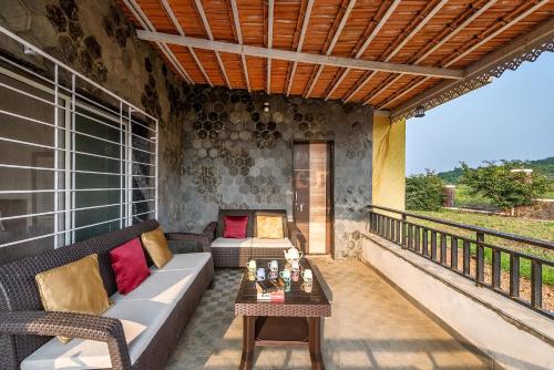 a patio with a couch and a table on a balcony at CosmicStays Rajgad Vista - Stay & play: adventure awaits in Welhe