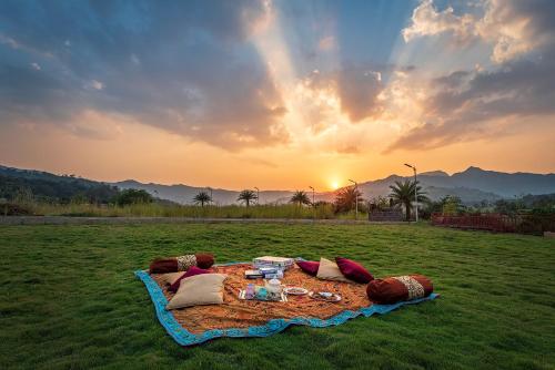 a picnic on a blanket in a field with the sunset at CosmicStays Rajgad Vista - Stay & play: adventure awaits in Welhe