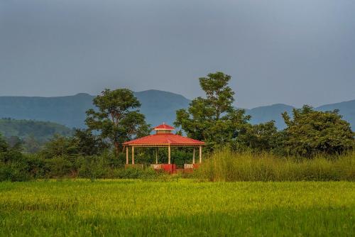 a gazebo with a red roof in a field at CosmicStays Rajgad Vista - Stay & play: adventure awaits in Welhe