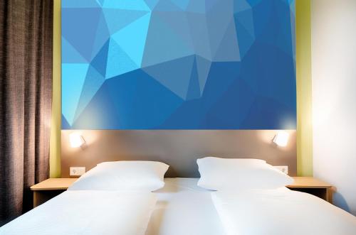 2 camas en una habitación con un cuadro en la pared en B&B Hotel Wolfsburg-Weyhausen en Wolfsburg