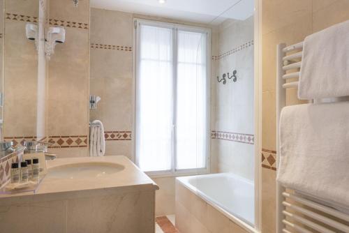 La salle de bains est pourvue d'un lavabo, d'une baignoire et d'une fenêtre. dans l'établissement Acacias Etoile, à Paris