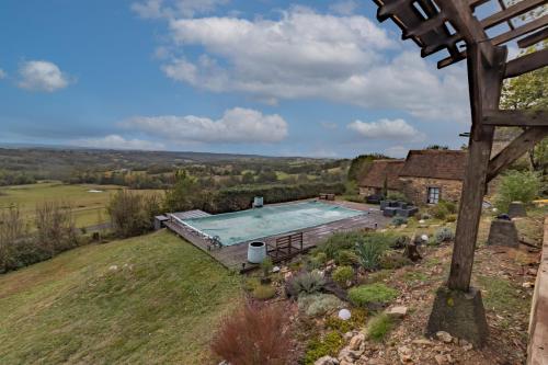 d'une vue sur la piscine sur une colline avec une maison. dans l'établissement La Dordogne en Périgord, à Salagnac