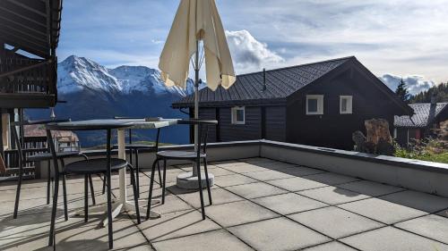 a patio with a table and chairs and an umbrella at Imhof Alpine B&B Apartments in Bettmeralp