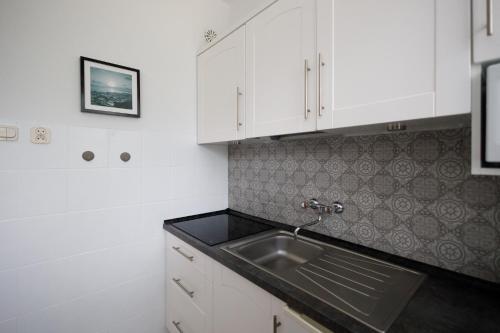 uma cozinha com armários brancos e um lavatório em Apartament Miriada 16 em Rowy