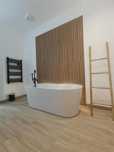 a white bath tub in a room with a wooden wall at Cocon haut de gamme à Nevers in Nevers