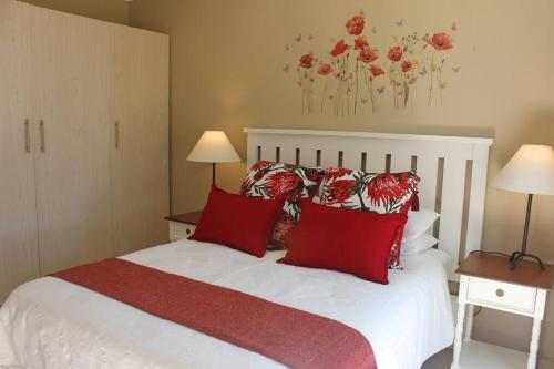 a bedroom with a white bed with red pillows at Tarentaal in Bloemfontein