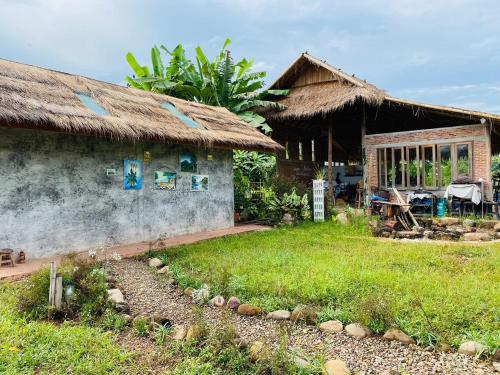 a house with a grass roof and a yard at PANAKLUEA Cottage & Crafts - พนาเกลือ in Ban Kham