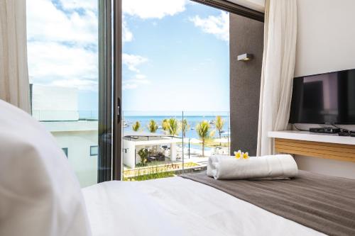 a bedroom with a large window with a view of the ocean at Latitude By Horizon Holidays in Rivière Noire