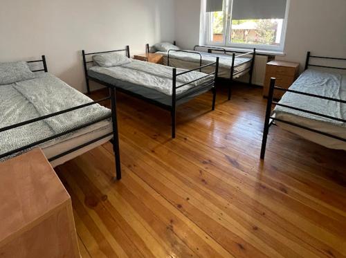 three beds in a room with a wooden floor at MY.PK.HOSTEL in Poznań
