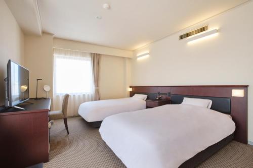 a hotel room with two beds and a flat screen tv at 高松パークホテル in Takamatsu