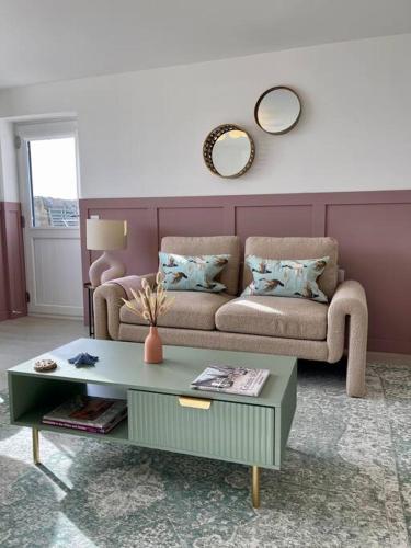 a living room with a couch and a table at Lighthouse Cottage With Hottub in Aberdeen