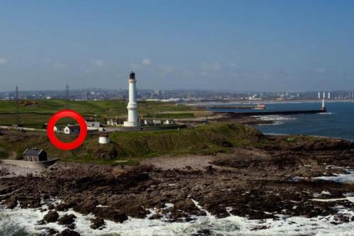 a lighthouse with a red circle in front of it at Lighthouse Cottage With Hottub in Aberdeen
