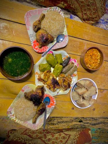 a wooden table topped with plates of food and dips at Heissa Hostel in Aswan