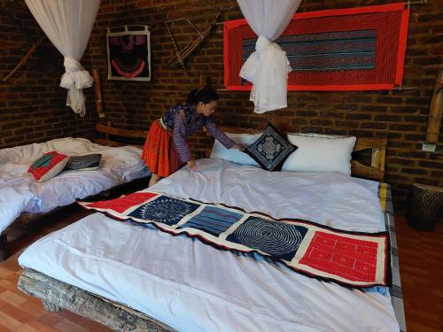una mujer de pie en dos camas en una habitación en A La Homestay en Hòa Bình