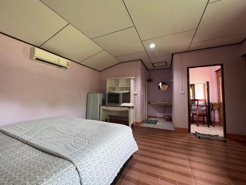 a bedroom with a white bed and a kitchen at Phet Ban Suan Hotel in Ko Chang
