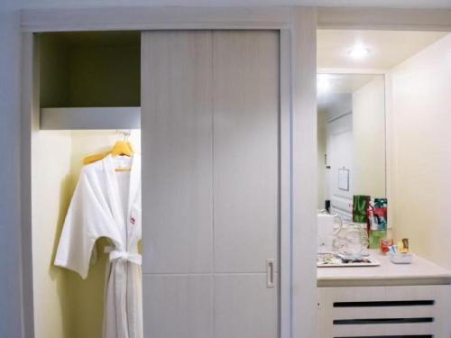 a bathroom with a shower with a white robe at The Palazzo Hotel in Bangkok