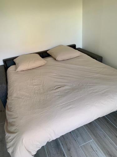 un lit avec deux oreillers dessus dans une chambre dans l'établissement Studio indépendant + jardin, à La Frette-sur-Seine
