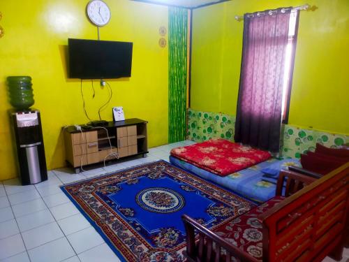 Habitación con cama, TV y alfombra. en Penginapan sweety homestays & Villas, en Ciwidey