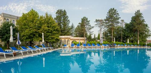 una grande piscina con sedie blu e alberi di Legends Tskaltubo Spa Resort a Tskhaltubo