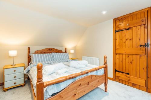 a bedroom with a wooden bed and a wooden door at Valley View at Clauchan Holiday Cottages in Gatehouse of Fleet