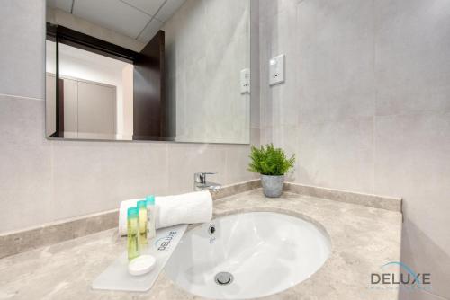 a bathroom with a white sink and a mirror at Vivid 2BR at Canal Residences West Dubai Sports City by Deluxe Holiday Homes in Dubai
