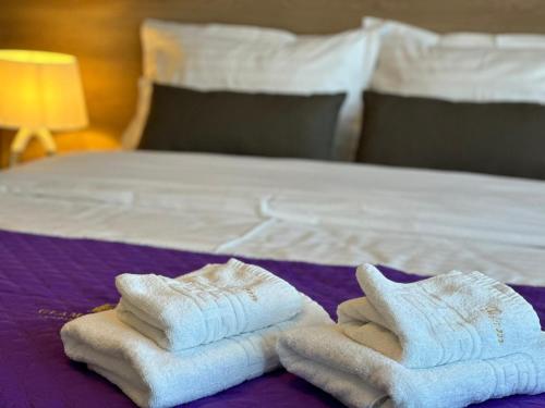 twee opvouwbare handdoeken bovenop een bed bij Luxury Glam Apartments & Studios near Coresi Mall in Braşov