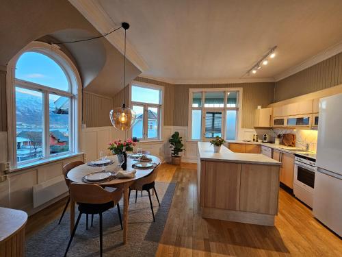een keuken met een tafel en stoelen en een keuken met ramen bij Lovely city center apartment with amazing views and free parking! in Tromsø