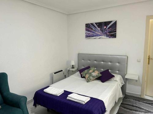 a bedroom with a bed with purple pillows and a chair at Estudio en Plaza del Callao Madrid Xs in Madrid