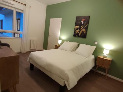 una camera con un letto bianco e una parete verde di Zenao Appart'hôtels Montivilliers a Montivilliers