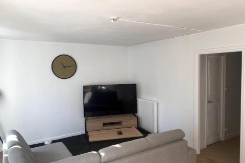 - un salon avec un canapé et une horloge murale dans l'établissement Bienvenue au P'tit Lou, à Boulogne-sur-Mer