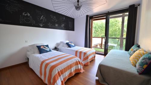 une chambre avec deux lits et un canapé et une fenêtre dans l'établissement BISCALODGE, à Biscarrosse