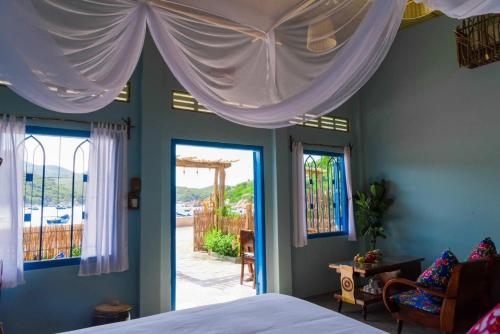 a bedroom with a bed and two windows with curtains at La Mer - Vĩnh Hy bay - beachfront villa CHÀI in Vĩnh Hy