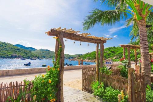 un arco de madera en una playa con palmeras en La Mer - Vĩnh Hy bay - beachfront villa CHÀI en Vĩnh Hy