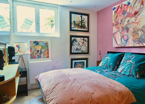 een slaapkamer met een bed en schilderijen aan de muur bij The Iflissen Nest - Luxury Appartment in Lamorlaye