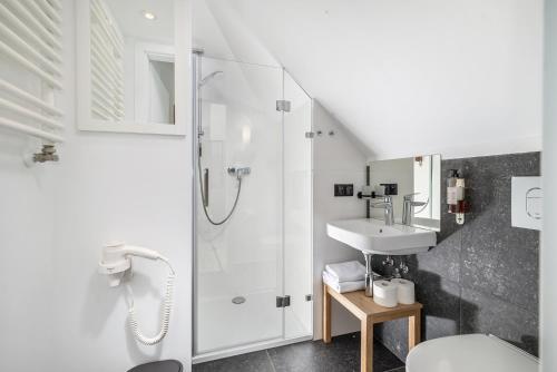 biała łazienka z prysznicem i umywalką w obiekcie Grand Tulipan w mieście Gdynia