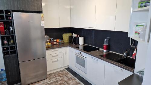 a kitchen with white cabinets and a stainless steel refrigerator at Luxury Apartment in Nis in Niš
